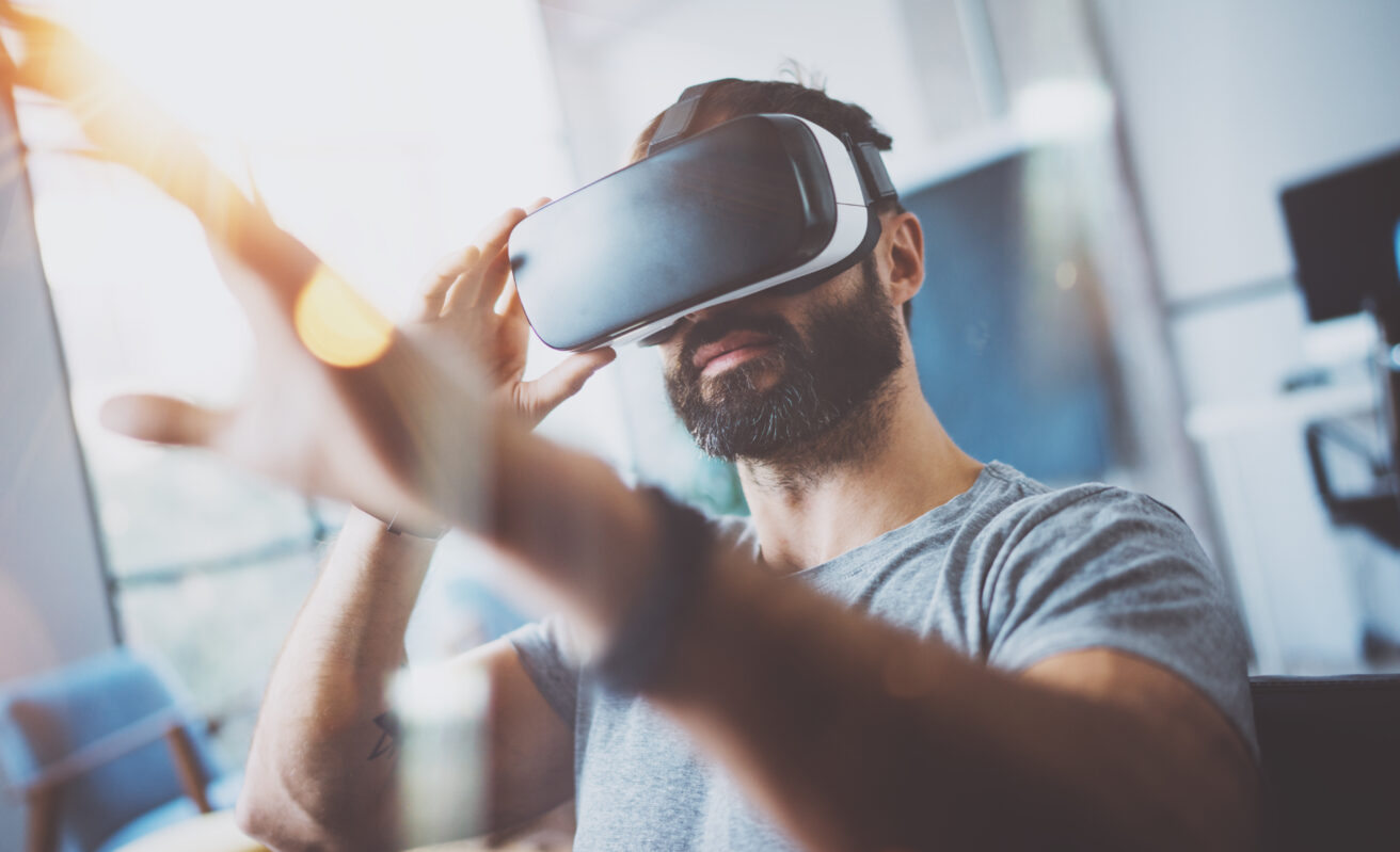 Closeup of bearded young man wearing virtual reality goggles.