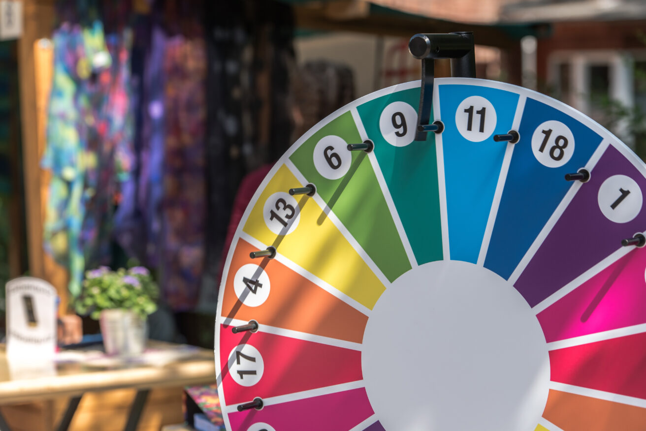 Rainbow colored prize wheel with in front of abstract background. 