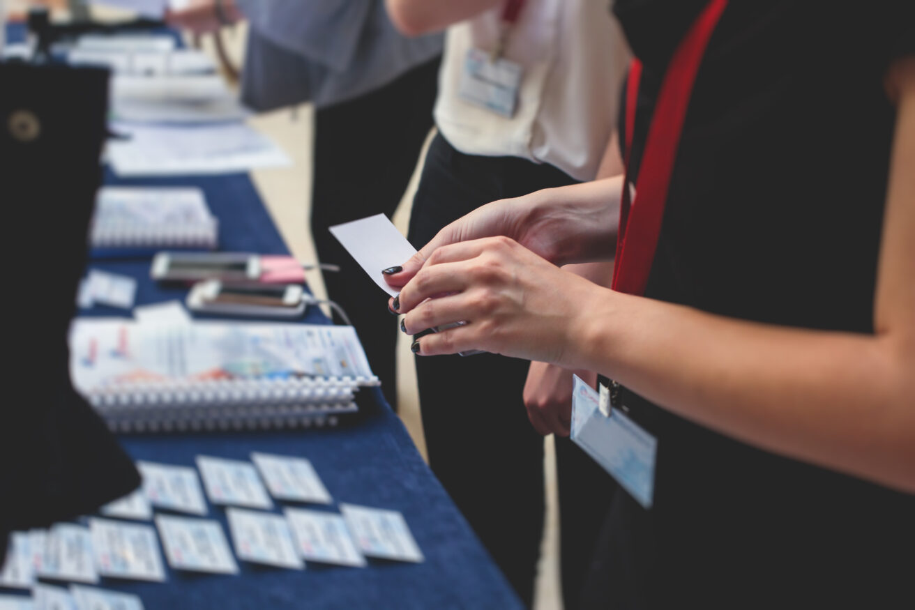 Process of checking in on a conference congress forum event, registration desk table, visitors and attendees receiving a name badge and entrance wristband bracelet and register the electronic ticket